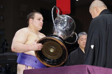 Ukrainian wrestler sekiwake Aonishiki receives the Emperor’s Cup from Japan Sumo Association head Hakkaku after winning the 15-day Kyushu Grand Sumo Tournament in Fukuoka, Japan, on November 23, 2025. (Source: Getty Images)