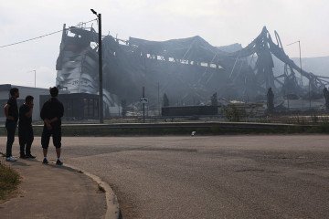 Passersby look at the burned-out warehouse of the logistics and trading company Wildberries in the Koledino industrial park, on August 17, 2026, in Podolsk, Russia. (Source: Getty Images)