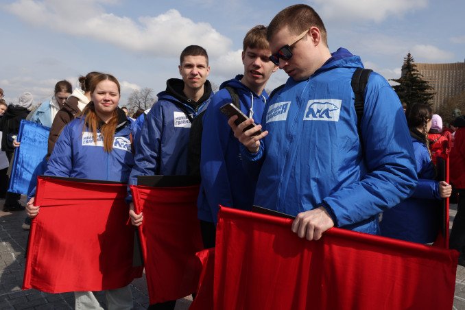 oven activista de movimiento pro Kremlin usa su smartphone frente al Monumento a los Conquistadores del Espacio en Moscú, abril 2026. Plan de vigilancia masiva online Rusia 2026-2030.