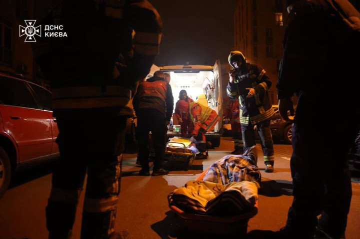 Los equipos de rescate evacuan a un herido en camilla a una ambulancia durante las operaciones nocturnas tras los ataques rusos. (Fuente: Servicios de Emergencia de Kyiv)