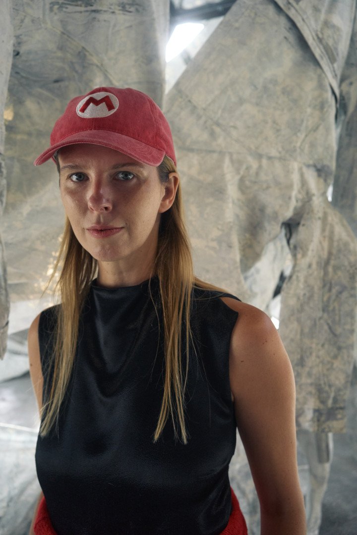 Maria Lanko, curator and co-owner of the Naked Room Gallery, organized the exhibition’s public program “Addressing the Concealed.” She stands in front of Ai Weiwei’s new installation, Three Perfectly Proportioned Spheres and Camouflage Uniforms Painted White, on September 14 at the Kyiv Pavilion of Culture. (Source: UNITED24 Media/Joshua Olley)