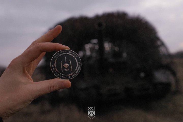 A Ukrainian soldier holds the 92nd Assault Brigade Tank Battalion insignia in front of the seized T-80BVM tank. (Photo 92nd Assault Brigade)