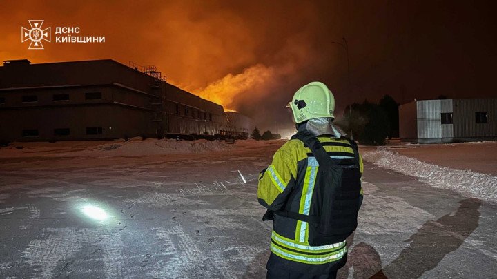 A firefighter monitors a blaze consuming a section of an industrial facility after a Russian drone hit the area amid a broader aerial assault. (Photo: DSNS Kyiv Region)