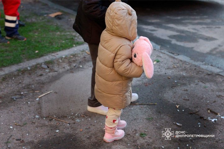 A child holds a toy near a damaged area after a Russian attack in Dnipro, April 25, 2026. (Source: State Emergency Service of Ukraine in Dnipropetrovsk region)