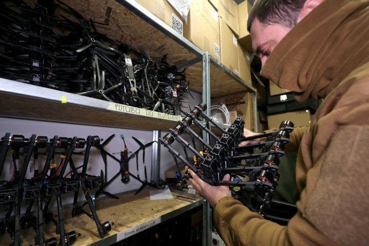 Un especialista sostiene una pila de drones FPV en el taller de vehículos aéreos no tripulados (VANT) de un batallón operativo de la 13.ª Brigada Khartiia de la Guardia Nacional de Ucrania, en la región de Kharkiv, Ucrania, el 17 de noviembre de 2025. Los expertos ensamblan, actualizan y reparan drones de reconocimiento y combate que cumplen con los requisitos operativos de la unidad en condiciones de campo. (Foto de Viacheslav Madiievskyi/Ukrinform/NurPhoto vía Getty Images)