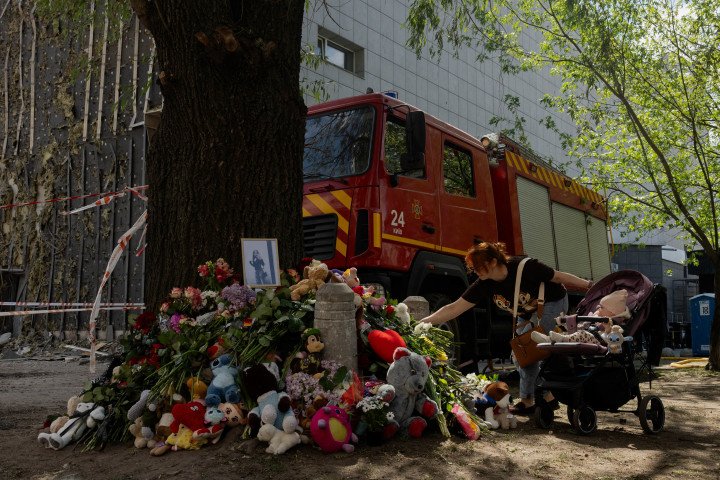 Residents lay flowers at a memorial near a residential building damaged in a Russian strike in Kyiv on May 15, 2026. (Source: Getty Images)