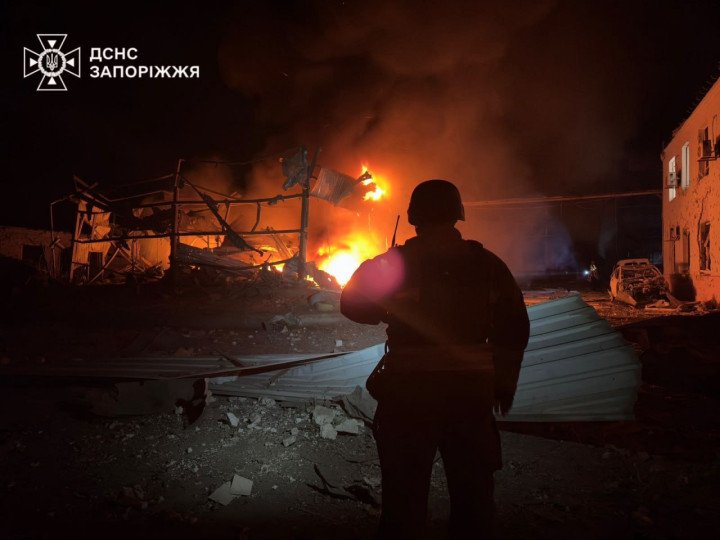 A Ukrainian emergency responder stands before burning debris after a Russian strike on an industrial facility in Zaporizhzhia, October 5, 2025. (Source: State Emergency Service of Ukraine, Zaporizhzhia Region)