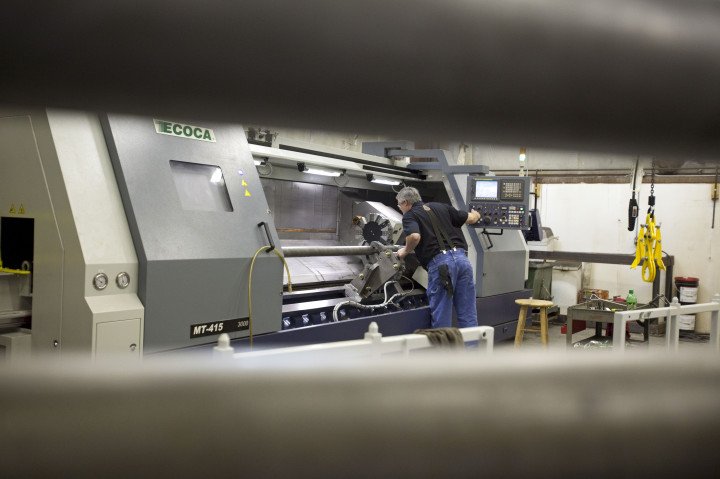 A worker operates a CNC lathe to produce Windspire wind turbine components at MasTech Manufacturing in Manistee, Michigan, illustrating the use of CNC machines in high-precision industrial production. (Source: Getty Images) A worker operates a CNC lathe to make Windspire wind turbine components at MasTech Manufacturing in Manistee, Michigan, illustrating CNC machines used in high-precision industrial production. (Source: Getty Images)