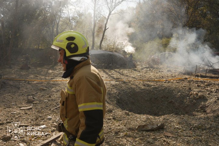 A Ukrainian emergency responder stands near a crater at the site of a Russian ballistic missile attack in Kyiv on October 10, 2026. (Source: State Emergency Service of Ukraine)