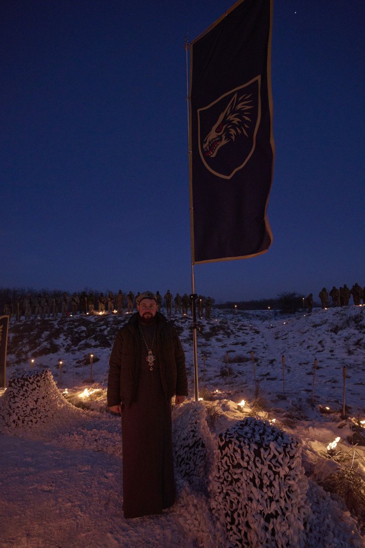 The center’s priest stands in front of their iconic wolf head flag. March 2026. Photo by Joshua Olley/UNITED24 Media.