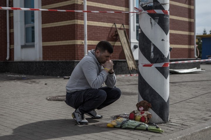 Un hombre coloca flores mientras los voluntarios buscan pistas para ayudar a identificar los cuerpos en la estación de tren de Kramatorsk después del ataque con misiles, el 9 de abril de 2022. (Fuente: Getty Images)
