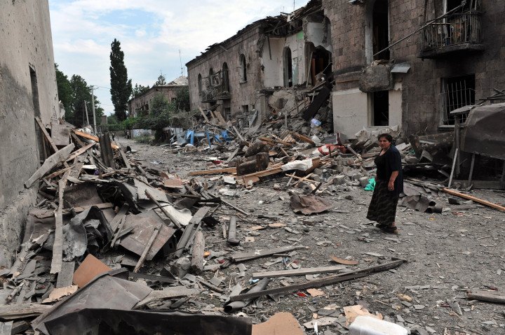 Una mujer georgiana pasa junto a un edificio alcanzado por un bombardeo en Gori el 9 de agosto de 2008. El presidente georgiano Mikheil Saakashvili declaró el estado de guerra ese mismo día, mientras sus tropas combatían contra las fuerzas rusas en la provincia separatista de Osetia del Sur. Aviones de guerra rusos bombardearon la ciudad georgiana de Gori, causando la muerte de civiles. (Fuente: AFP vía Getty Images)