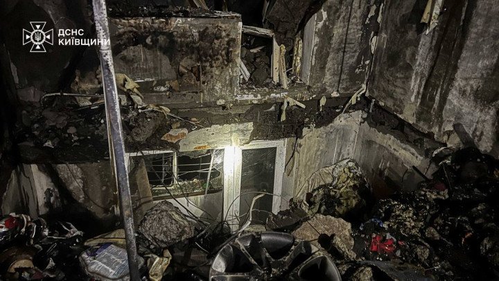 Una vista a nivel del suelo muestra paredes derrumbadas, escombros estructurales y materiales quemados después de un ataque a un edificio civil en la región de Kyiv. (Fuente: Servicios de Emergencia de la Región de Kyiv)