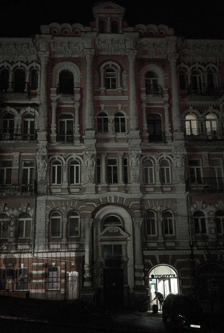 Un edificio histórico de principios del siglo XX en el centro de Kyiv permanece casi a oscuras debido a los apagones, con solo una tienda en la planta baja iluminada por un generador. 18 de noviembre de 2025. Foto de Joshua Olley/UNITED24 Media.