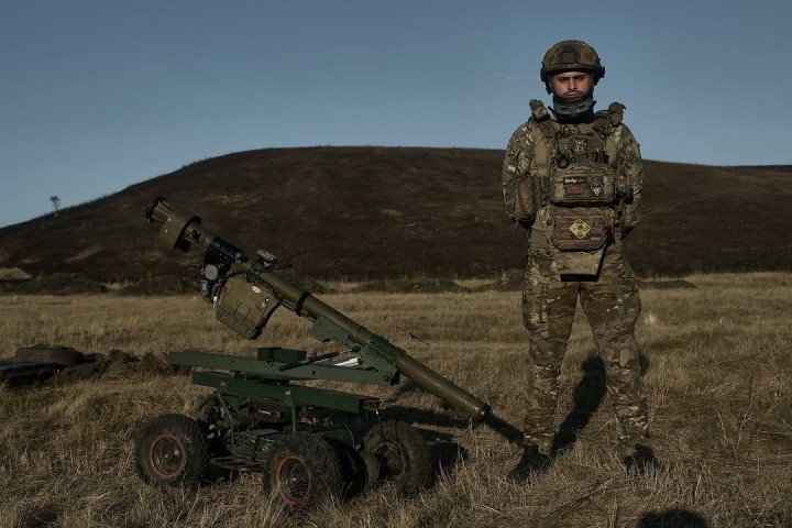 A member of Ukraine’s 28th Mechanized Brigade stands beside the brigade’s improvised robotic missile launcher. (Source: Libkos)