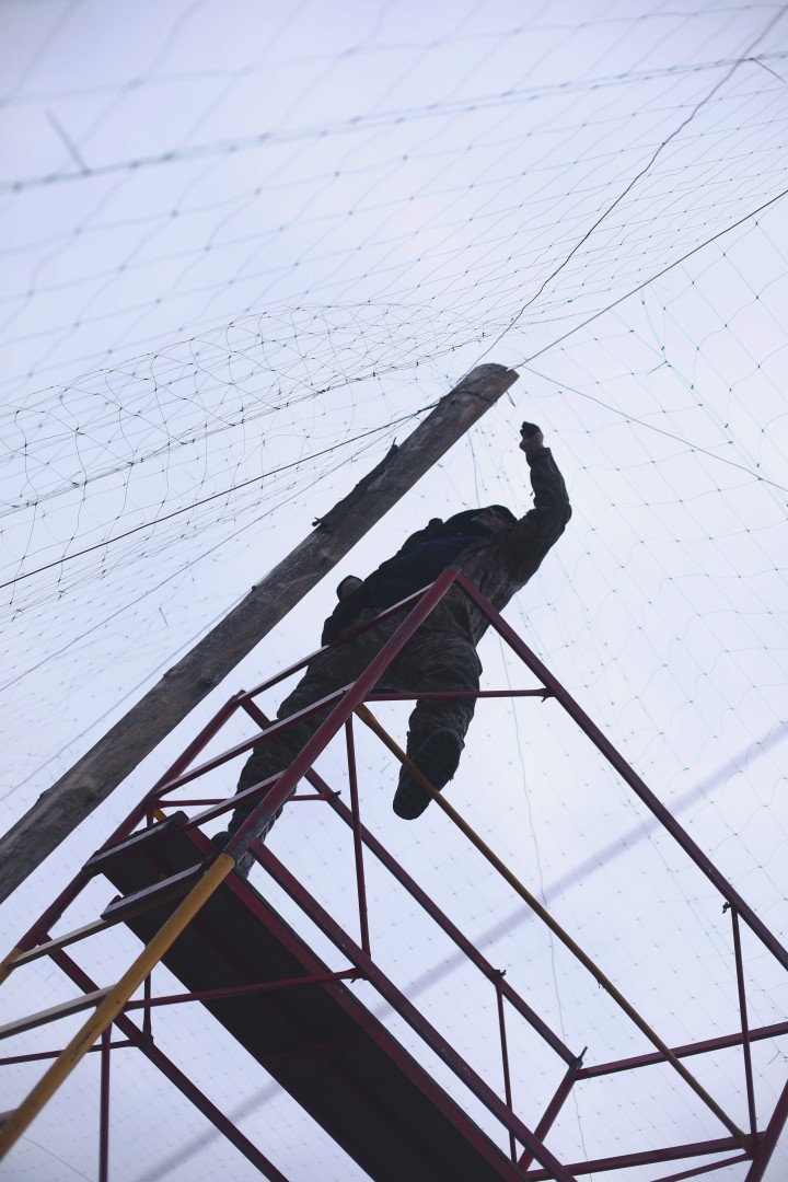 Un soldado repara agujeros en la red antidrones que cubre una carretera cerca de Izium, en la región de Kharkiv, Ucrania, marzo de 2026. (Foto: Lucile Brizard/UNITED24 Media) Red antidrones que cubre una carretera cerca de Izium.