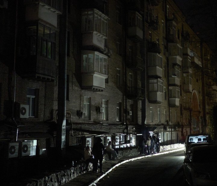 Los faros de un coche que pasa iluminan a grupos de adolescentes que pasan el rato en el centro de Kyiv a última hora de la tarde. 18 de noviembre de 2025. Foto de Joshua Olley/UNITED24 Media.