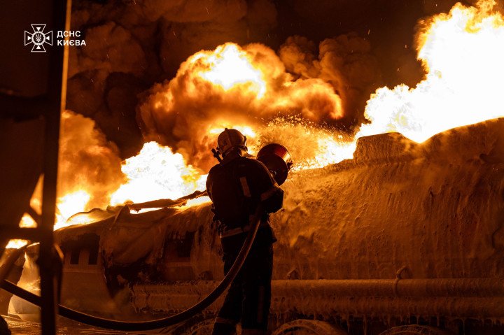 A firefighter battles a massive blaze engulfing a fuel tanker or industrial structure following a drone or missile strike. (Photo: Kyiv Emergency Service)