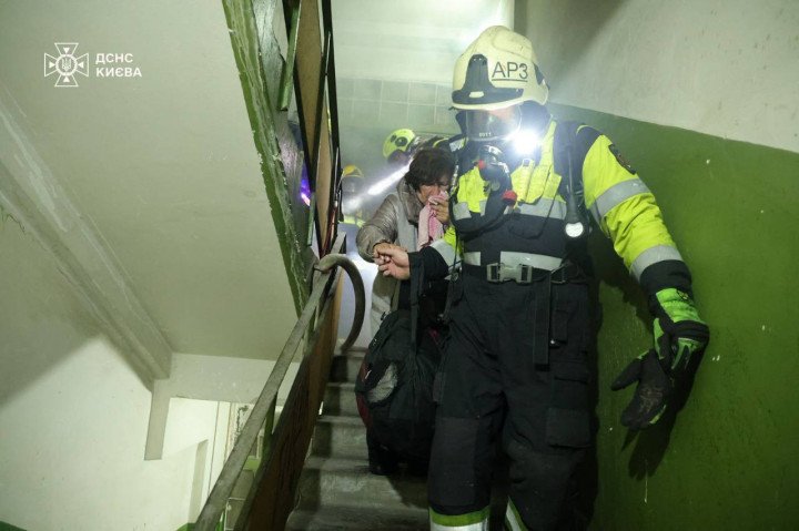 Rescuers evacuate a woman from a smoke-filled apartment building in Kyiv after a Russian drone strike on October 10, 2025. (Source: SES)