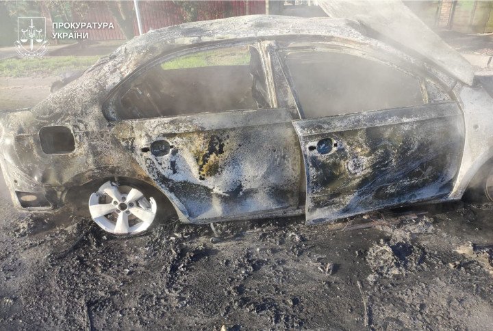 A burned-out civilian vehicle in Nikopol following a Russian strike, with debris scattered across the roadway. (Source: Ukrainian Prosecutor’s Office)