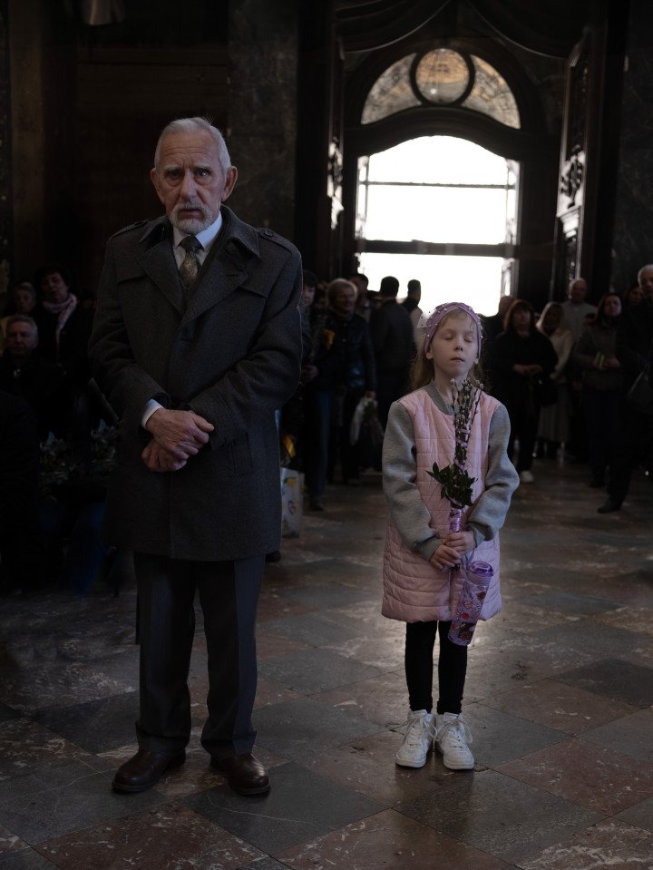 A grandfather and granddaughter stand side by side on Palm Sunday at Sts. Peter and Paul Garrison Church. April 2025. A grandfather and granddaughter stand side by side on Palm Sunday at Sts. Peter and Paul Garrison Church. April 2025.