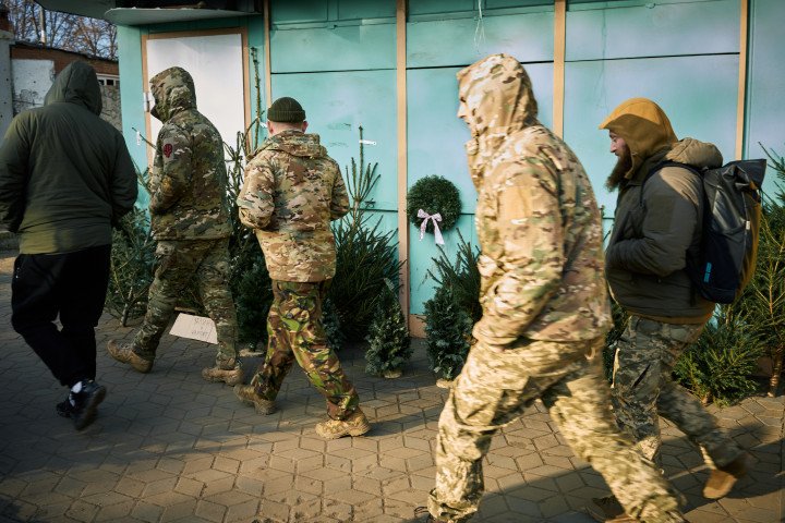 A soldier glances at Christmas trees being sold on the street. Izium, Ukraine. December 24, 2025. Photo by Joshua Olley/UNITED24 Media. A soldier glances at Christmas trees being sold on the street. Izium, Ukraine. December 24, 2025. Photo by Joshua Olley/UNITED24 Media.