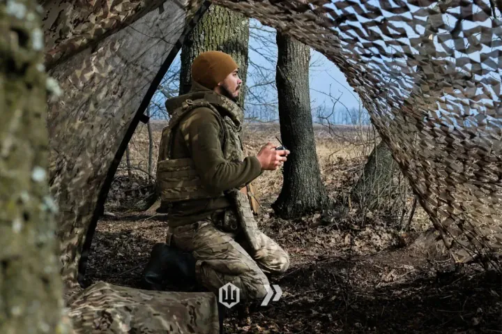 A Ukrainian drone operator monitors field conditions from a concealed, camouflaged position. (Photo: 413th Separate Unmanned Systems Regiment Raid)
