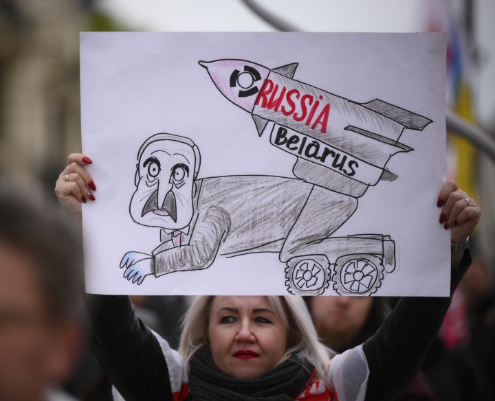 A woman holds a sign with an representation of Belarusian leader Alexander Lukashenko with a nuclear missile during a rally in Warsaw, Poland on 26 April, 2023. (Photo by Jaap Arriens/NurPhoto via Getty Images)