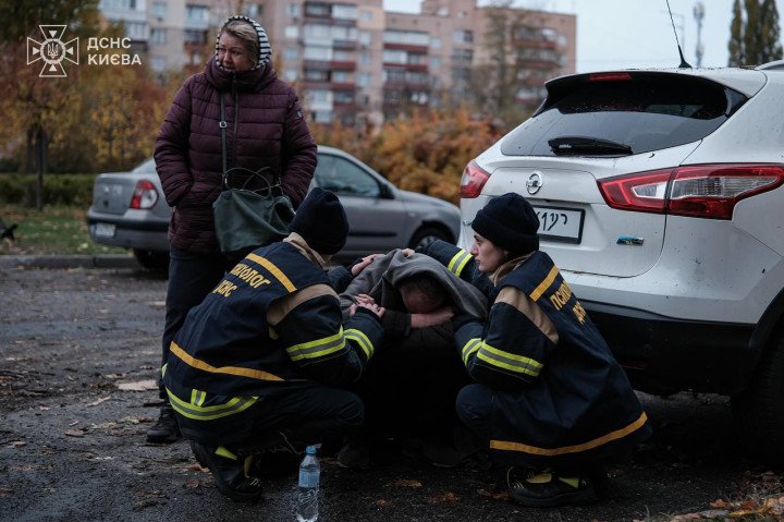 Ukrainian emergency responders assist a distressed resident near a damaged vehicle after a drone attack in Kyiv’s residential area. (Source: DSNS Kyiv)