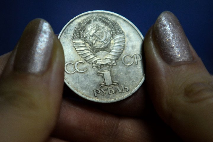 A woman holds a Soviet ruble coin (Photo by KIRILL KUDRYAVTSEV/AFP via Getty Images).