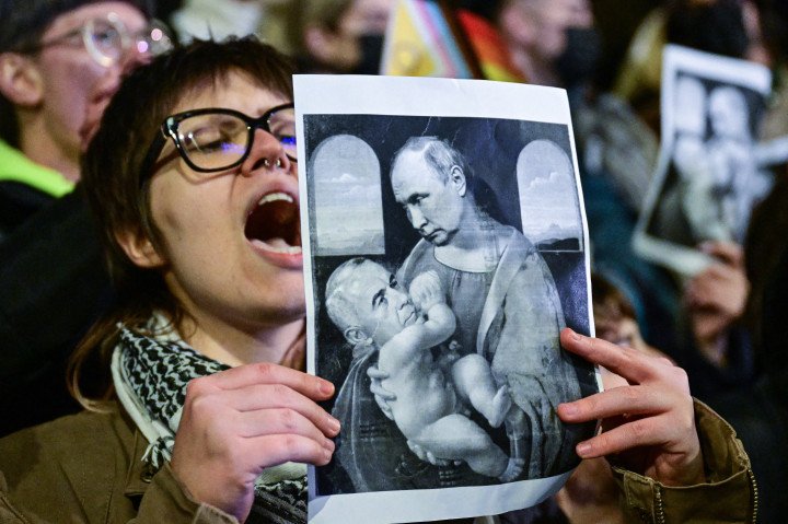 A demonstrator holds a satirical image of Da Vinci's "Madonna and Child" painting depicting Russia's President (Top) breastfeeding Romania's presidential candidate, Catalin Georgescu during a protest against Catalin Georgescu, winner in the first round of Romania's presidential elections in Bucharest, on November 25, 2024. (Photo by DANIEL MIHAILESCU/AFP via Getty Images) A demonstrator holds a satirical image of Da Vinci's "Madonna and Child" painting depicting Russia's President (Top) breastfeeding Romania's presidential candidate, Catalin Georgescu during a protest against Catalin Georgescu, winner in the first round of Romania's presidential elections in Bucharest, on November 25, 2024. (Photo by DANIEL MIHAILESCU/AFP via Getty Images)