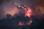 A French Civil Security Canadair CL-415 aircraft flies past flames burning a forest surrounding Cotignac, southeastern France, on July 23, 2026, during a wildfire.