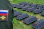 A Russian soldier stands beside rows of black coffins. (Source: Getty Images)