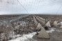 Concrete dragon’s teeth and razor wire fortifications are seen stretching across a field in the Kharkiv region behind a protective anti-drone net, January 7, 2026. (Source: Getty Images)
