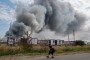 A Wildberries emloyee walks past a plume of smoke rises during a fire at Russian e-commerce firm Wildberries' logistics complex near the town of Podolsk, outside Moscow on August 16, 2026. (Source: Getty Images)