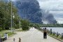 People walk in a park as black smoke rises from the area of the Russian oil producer Gazprom Neft’s Moscow oil refinery on the south-eastern outskirts of Moscow on June 18, 2026. (Source: Getty Images)