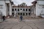 Locals of Kostiantynivka riding past a building hit by a Russian strike.