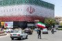 A man is seen waving an Iranian flag in front of a billboard displaying the Iranian flag on June 15, 2026 in Tehran, Iran. (Source: Getty Images)