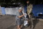 A resident casts a ballot during Russian-organized early voting in the Russian-occupied Donetsk region as an armed serviceman stands beside a mobile ballot box, September 14, 2026.