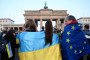 A participant wearing the European flag looks at young women with the Ukrainian flag in front of the landmark Brandenburg Gate in Berlin on March 9, 2025, during a demonstration in support of Ukraine. (Source: Getty Images)