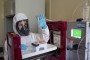 A lab technician wearing personal protective equipment (PPE) places vials into a chromatography machine. (Source: Getty Images)