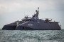 The dark-grey, stealth-designed Iranian catamaran warship Soleimani sails on open water, carrying a helicopter on its rear deck. (Source: Tasnim News Agency)