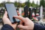 A person uses a smartphone at a cemetery. (Photo: Open source)