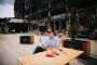 Political commentator Laura Loomer eats McDonald’s at an outdoor table in Kyiv with a blast-damaged building in the background. (Source: X / Laura Loomer)